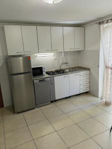 a kitchen with white cabinets and a stainless steel refrigerator at Apartman Aurora in Ičići