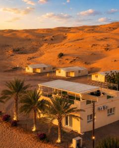a house in the middle of a desert with palm trees at Remal Desert Retreat Bidiyah in Badīyah
