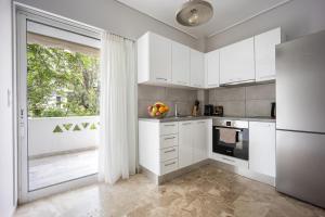 a kitchen with white cabinets and a large window at City Center Calm Spot in Athens