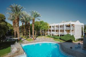 a pool in front of a hotel with palm trees at Royal Park Apartments Resort by Sea N Rent in Eilat