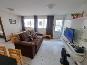 a living room with a couch and a flat screen tv at Apartamento Enseada Beach Residence completo in Cabo de Santo Agostinho