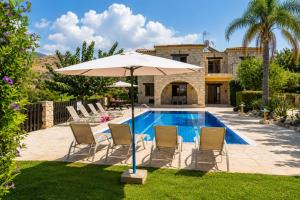 a patio with chairs and an umbrella next to a pool at Villa Androulla in Argaka