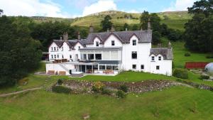 a large white house on top of a green field at Stucktaymore in Killin