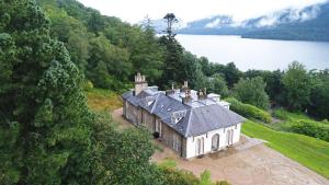 an old house on a hill next to a lake at Stuckgowan in Arrochar