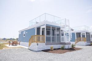 a large blue house with a porch and a deck at Chincoteague Bay RV Resort & Cottages in Chincoteague +16 photos