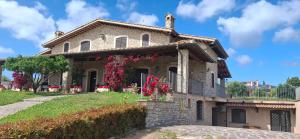 a stone house with red flowers on it at Villa Klinai in Cerveteri