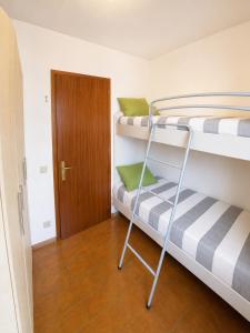 a room with two bunk beds and a wooden door at Condominio Cristina - Agenzia Cocal in Caorle