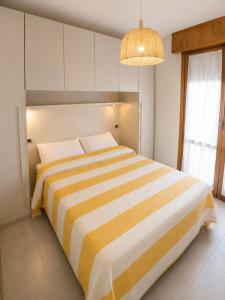 a bedroom with a yellow and white striped bed at Condominio Cristina - Agenzia Cocal in Caorle