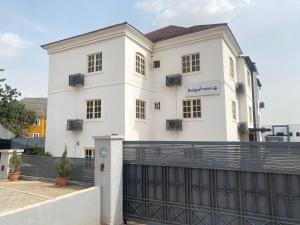 a white house with a fence in front of it at Bridgewaters Hotel in Abuja
