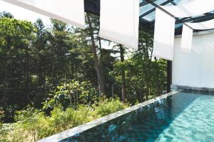 a swimming pool in the middle of a house with trees at Tivoliville Spa N Poolvilla in Pocheon