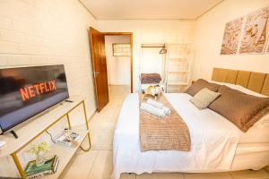 a small room with a bed and a flat screen tv at Apartamento com Café no 1º Dia, Kit Fondue e Aquecedor no Quarto a 300m da Praia para Casais in Imbituba