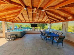 a large patio with a table and a hot tub at Villa Solaris in Donje Rašćane