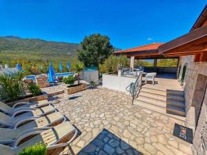 a patio with chairs and a deck with a pool at Villa Solaris in Donje Rašćane