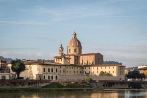 a building with a dome on top next to a river at BYPILLOW Del Presto in Florence