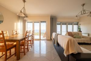 a living room and dining room with a table and a bed at Praça da Cultura Residence in Buarcos
