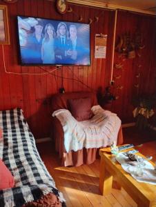 a room with a tv on a wall with a couch at Hospedaje Chumaihuen in Quellón