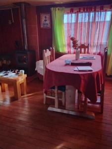 a dining room table with a red table cloth on it at Hospedaje Chumaihuen in Quellón +15 photos