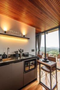 a kitchen with a sink and a table in a room at Studio Sunrise - Luxo, Romance e Natureza in Rancho Queimado