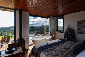 a bedroom with a bed and a bath tub and a window at Studio Sunrise - Luxo, Romance e Natureza in Rancho Queimado