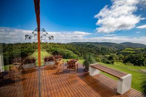 a deck with a bench and a view of the mountains at Studio Sunrise - Luxo, Romance e Natureza in Rancho Queimado