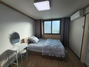 a bedroom with a bed and a desk and a mirror at Daecheon Sodam pension in Boryeong