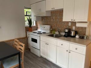 a kitchen with white cabinets and a white stove top oven at 2-Bedroom Suite in North Vancouver