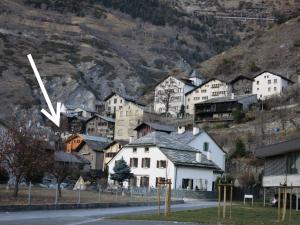 a clock in the middle of a town with a mountain at Apartment Rilkedorf Raron in Raron