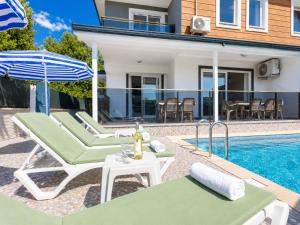 a villa with a swimming pool with chairs and an umbrella at Villa Azalea 1 in Ortaca