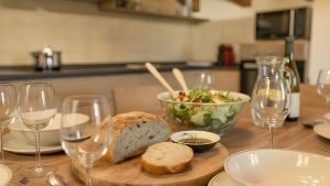 a table with a bowl of salad and bread and wine glasses at Chalet la Segheria in Temù