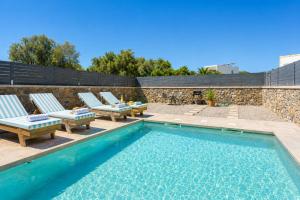 a swimming pool with lounge chairs next to a stone wall at La Casa Di Pietre 2 in Kiotari