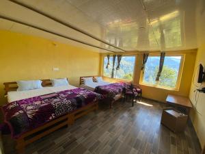 a bedroom with two beds and two windows at Hotel Chandra Paradise in Munsyari