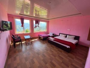 a bedroom with pink walls and a bed and a table at Hotel Chandra Paradise in Munsyari