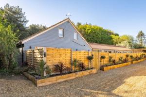 a house with a fence with plants in front of it at The Barn at Thorpewood in Thorpe Market