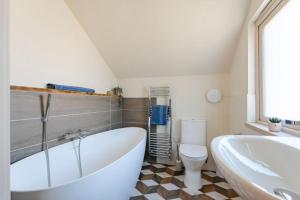 a white bathroom with a tub and a toilet at The Barn at Thorpewood in Thorpe Market +12 photos
