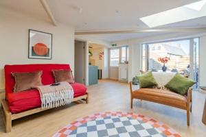 a bedroom with a red bed and two chairs at The Barn at Thorpewood in Thorpe Market