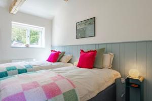 a bedroom with two beds with pink and green pillows at The Cove at Thorpewood in Thorpe Market