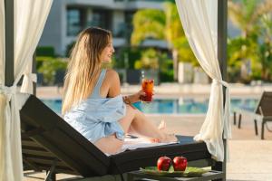 a woman sitting in a lounge chair with a drink at La Finca Resort in Algorfa +49 photos