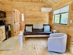 a living room with a leather couch in a log cabin at Cozy Coastal Cabin 5 in Steuben