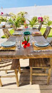 a wooden table with plates and a red flower on it at Villa Massalia Essaouira in Essaouira