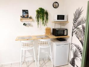 a kitchen with a counter with stools and a microwave at Studio cosy à Bas-du-Fort in Le Gosier