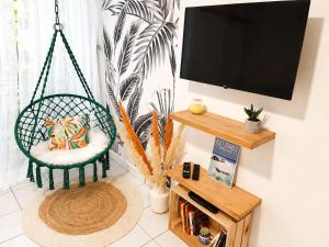 a room with a swing chair and a flat screen tv at Studio cosy à Bas-du-Fort in Le Gosier