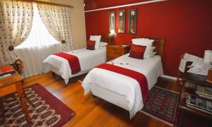 a bedroom with two beds and a red wall at Beau & I in Graaff-Reinet