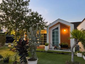 a house with trees and plants in a yard at Good life home in U Tapao
