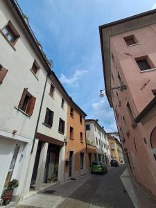an alley with buildings and a green car on a street at DolomitiBel Garibaldina in Belluno