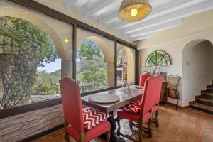 a dining room with a table and chairs and windows at Les Pigerolles de Cabris in Cabris