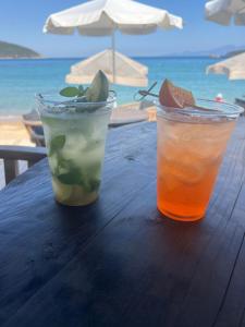 two cocktails sitting on a wooden table next to the ocean at Egee View in Nea Peramos