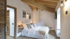 a bedroom with a white bed and wooden ceilings at Chalet Ferrari in Ponte di Legno
