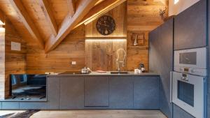 a kitchen with wooden walls and a clock on the wall at Alpen Chalet in Ponte di Legno