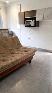 a brown couch in a kitchen with a microwave at Casa Ubatuba in Ubatuba