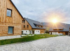 two houses with the sunset in the background at Designové chalupy v Jeseníkách - Přemyslovské stráně in Kociánov +61 photos